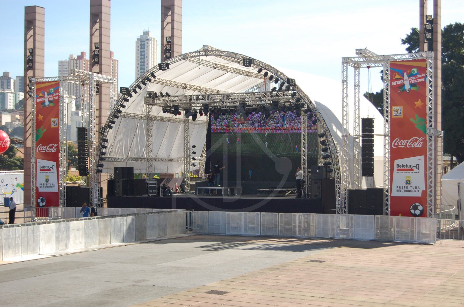 Palco com cobertura em arco de treliças, telões e grades de público